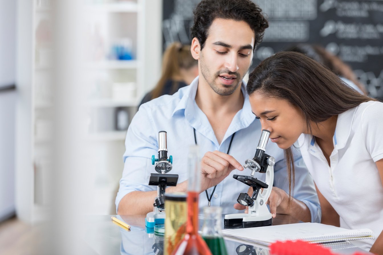 Teacher helps high school girl in biology class